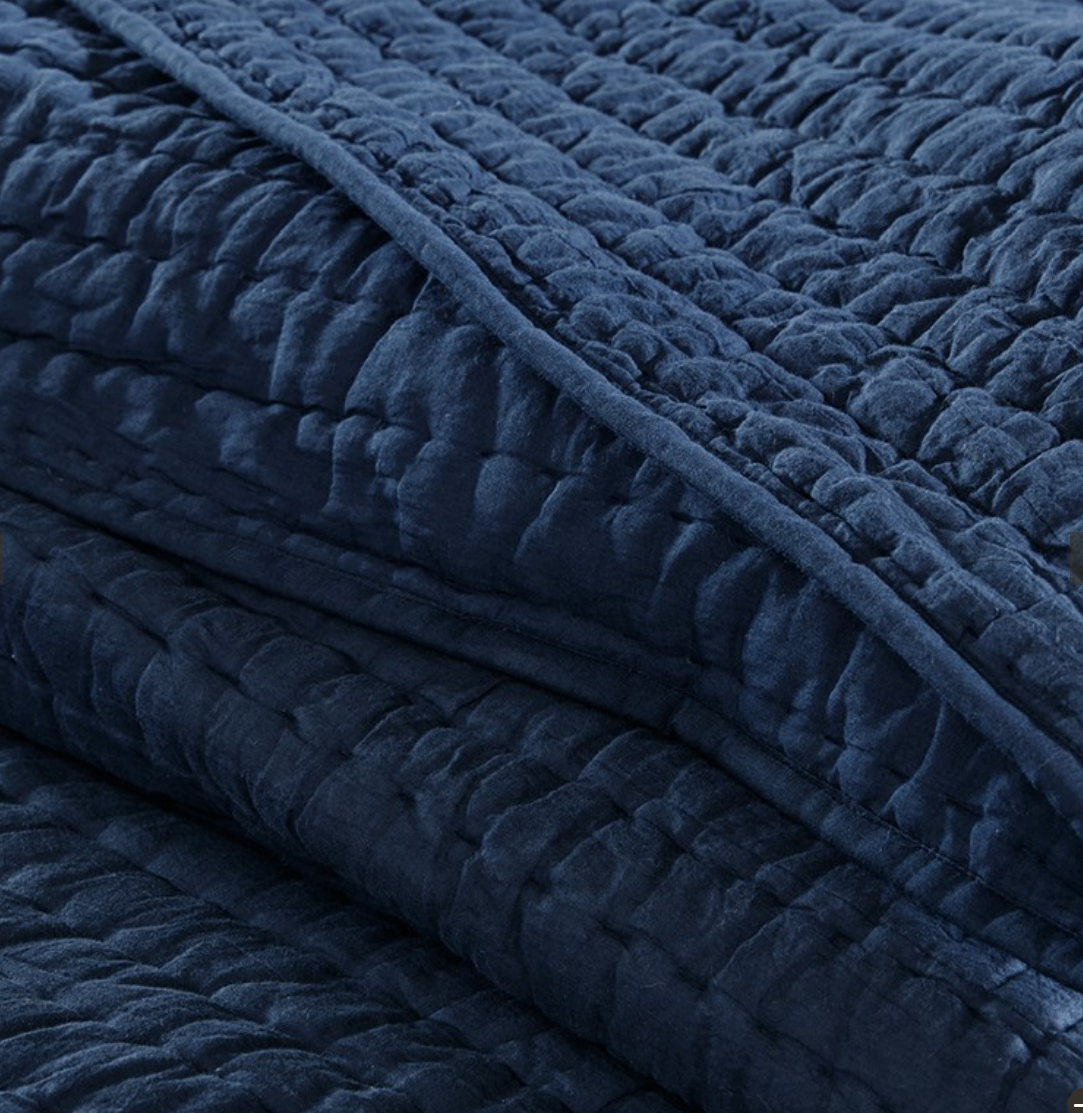 Navy oversized quilt with quilted texture, 100% cotton, folded with matching pillow shams.