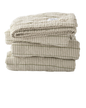 Heirloom‑inspired quilt folded featuring muted beige and olive green vertical stripes with soft textured stitching.